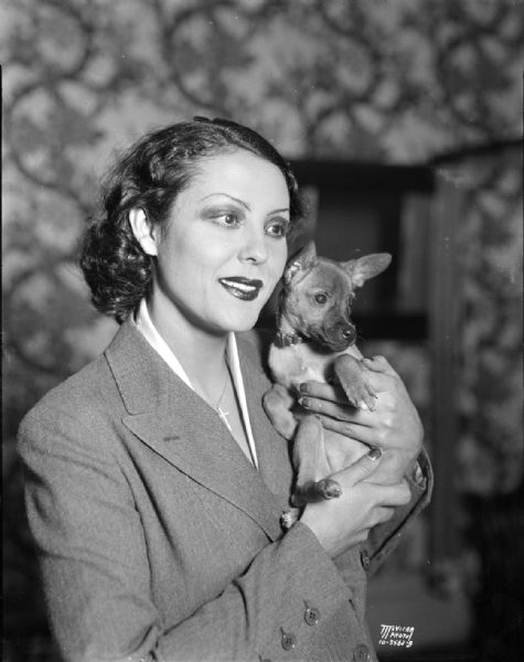 Portrait of Raquel Torres, actress and RKO star, holding a small dog.