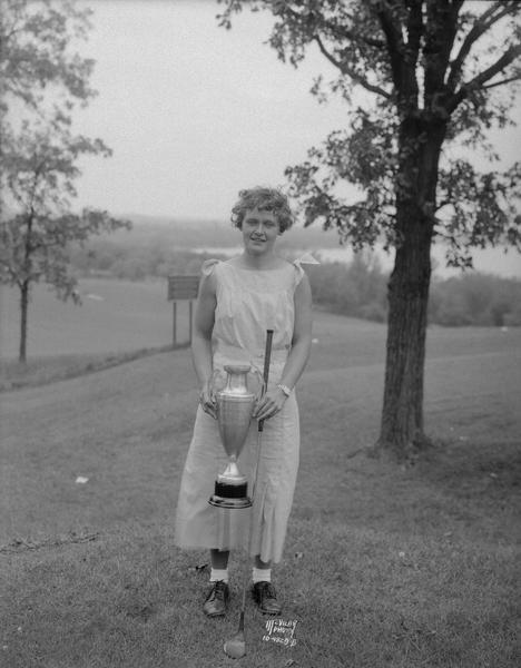 Harriet Gorman holding golf club and golf trophy at Blackhawk Country Club.