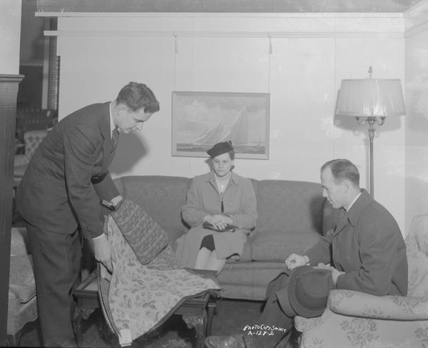 Lowell Frautschi displaying fabric samples to a couple sitting on living room furniture at Frautschi's, Incorporated, 219 King Street.