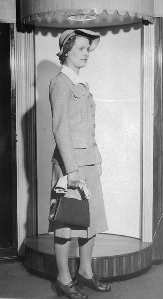 Simpson's, 23-25 North Pinckney Street. Woman modeling a suit, with hat, gloves and purse.