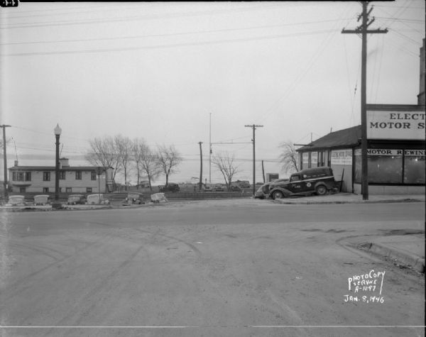 East Wilson Street scene at the center of South Hancock Street looking South down South Hancock Street across East Wilson Street, taken at site of Reynolds Bus accident. Businesses shown include the Four Lakes Boat Club at 1 South Hancock Street, and the Electric Motor Service at 323 East Wilson Street.