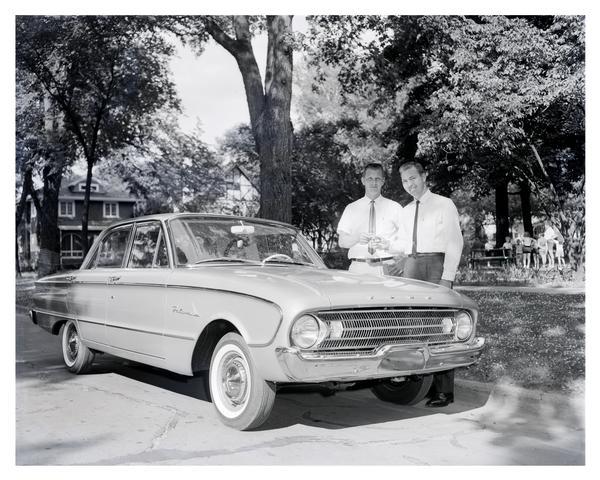 Bart Starr of the Green Bay Packers receives a new 1961 Ford Falcon from a Green Bay Ford dealer. The compact Falcon was introduced by Ford in 1959 to appeal to drivers seeking better mileage. It was available in several styles in addition to the four-door sedan seen here, including convertibles and station wagons, and it was immediately popular with car buyers. The Falcon also served as the framework for the Ford Mustang. Production of the Falcon in the United States ended in 1970.