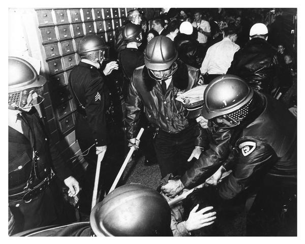 University of Wisconsin-Madison students clash with riot police during campus demonstration to protest Dow Chemical involvement in the Vietnam conflict. Here, several police officers with clubs hold a student down on the floor.