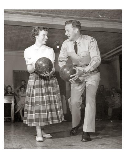 A USO volunteer challenges an enthusiastic soldier to a friendly bowling match.