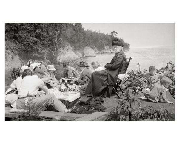 Picnic on the shores of Basswood Island, Apostle Islands. Those picnicking include Harriet Webb, C.A. Hull, H.W. Rodgers, Mrs. J. Austin, Elizabeth Baker, Mrs. J.L. Abernathy, and two Austin children.