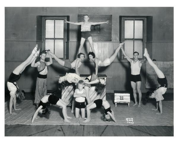 Twelve boys and girls, coached by J.C. Haberman, in an acrobatic/gymnastic pose at the Madison Turners Hall, 21 South Butler Street. They performed seven "acts" at the Policemen's Protective Association benefit picnic for The Capital Times Kiddie Camp fund at the French Village in Miller's Park on South Park Street.  Madison's Turnverein was founded in 1855 by German immigrants to encourage physical and mental development. 
