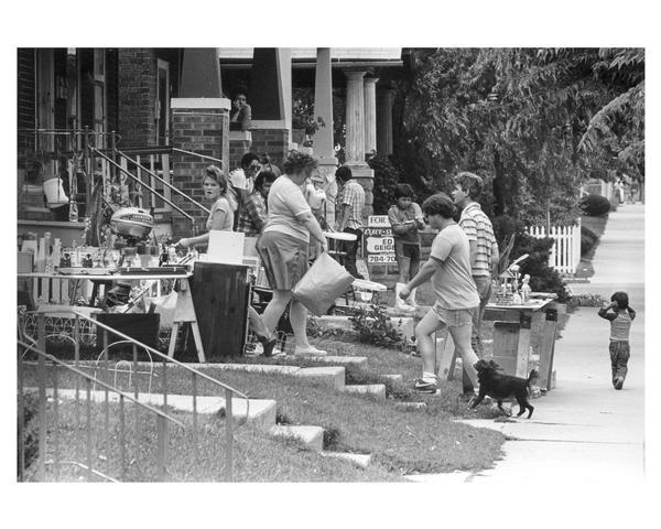 People working and shopping at a neighborhood garage sale in the Walker's Square Park area. Several neighborhood groups collaborated to sponsor the annual Southside Housing Fair and Flea Market, which featured booths on home buying, renovation, and legal matters, as well as several garage sales.