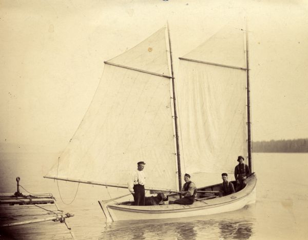 Ole Christinson, Dick Hanson, Fred Hanson, and Herman Johnson, Sr., onboard sailboat "Louis Moe" along the shore of Sand Island.