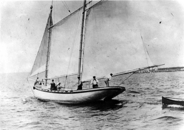 Three men and two women on board the <i>Lizzie W.</i> sailboat. Captain D.R. Angus, who is at the tiller, owned the <i>Lizzie W.,</i> which was named after Elizabeth Woods, the wife of Mr. Frederick Woods.