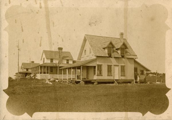 View of three of the early houses on Nebraska Row in La Pointe, Madeline Island. Haecker house is in the foreground, the Woods' house is next door.