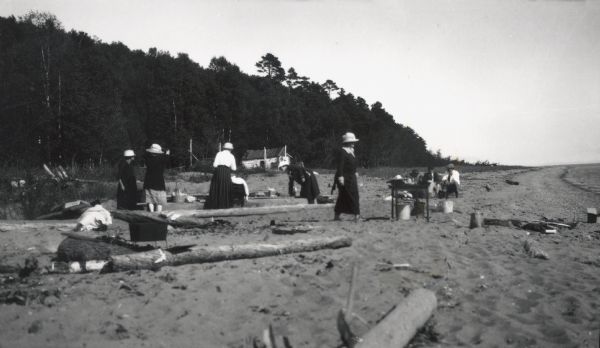 Picnic on beach of one of the Apostle Islands, Lake Superior. Image includes Mrs. Chute, Mrs. Webb., Mrs. Hull, H.W. Rogers and Mr. Chute.