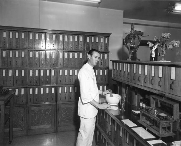 A pharmacist compounds materials with a large mortar and pestle in the dispensary of St. Joseph's Hospital.