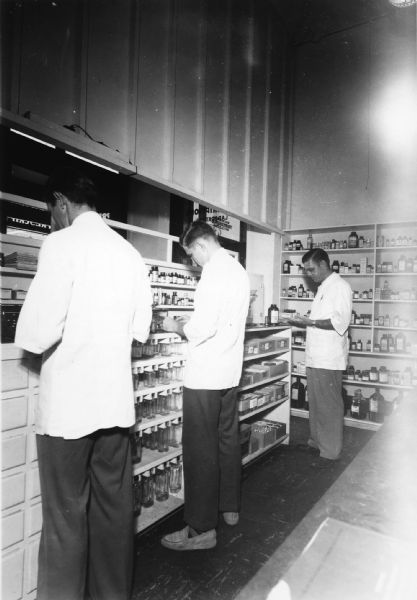 A trio of druggists busy themselves in the dispensary of Richards Brothers' Pharmacy.