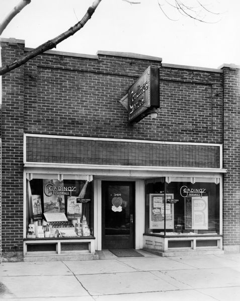 Exterior view of Gerding's Pharmacy. The display on the left is for Squibb's Aspirin. There are also several small signs indicating that the building is "air conditioned... for your comfort," which was something of a luxury for the time.
