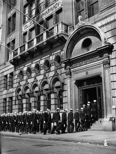 Pictured are the members of the U.S. Coast Guard Hospital Corps School heading to their pharmacy course in the Columbia University College of Pharmacy building. There were 200 people in each class, and the course required three months of intensive study before Guardsmen were prepared for active duty.