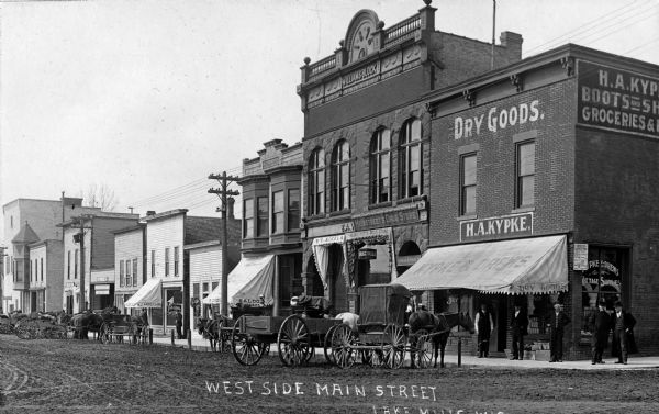 View of the west side of Main Street.  Stores pictured (right to left):  Kypke's Dry Goods store, Heimstreet's Drugstore, and a saloon.
