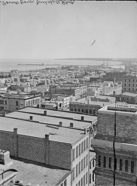 Milwaukee, towards South Point from Mitchell Block, E. Water Street and Michigan Street. Elevated view shows buildings and rooftops with bay and harbor in the distance.
