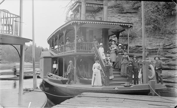 Passengers ng on the "Dell Queen" steamboat. The edge of a second steamboat is on the left.