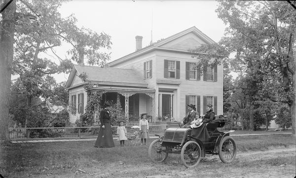 The H.H. Bennett House, Kilbourn, with members of the family posing in front of the house and in a 1901 Winton automobile. Ashley Bennett, the son of the famous photographer, is tentatively identified as the driver of the car which is so early that has a tiller rather than a steering wheel. Like his father, Ashley had a talent for tinkering and even experimented with building his own airplane. Ashley was in the automobile business in Minneapolis.