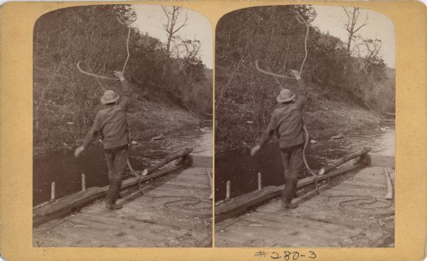 Stereograph of a man on a raft throwing a rope.