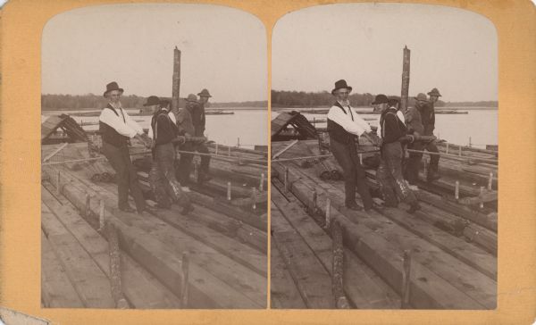 Stereograph view of five men on a raft working a Spanish windlass.