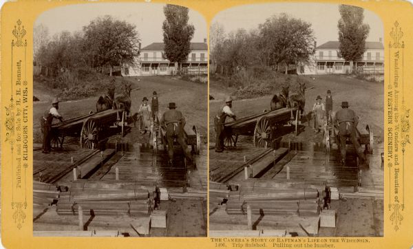 Stereograph of men unloading lumber off a raft. A man at the left is loading lumber onto a horse-drawn wagon, while a man in an apron is holding the horses. There is a boy standing in the center. On the right a man is loading lumber onto a second wagon. The rafts loaded with lumber are in the foreground. There is a large building on a hill in the background.
