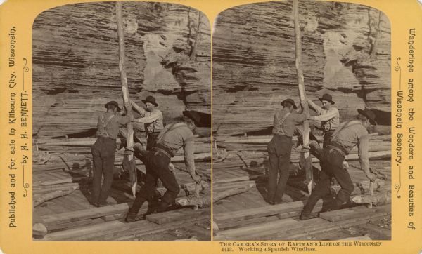 Stereograph of four men on a raft working a Spanish windlass. The raft is in front of a rock wall.
