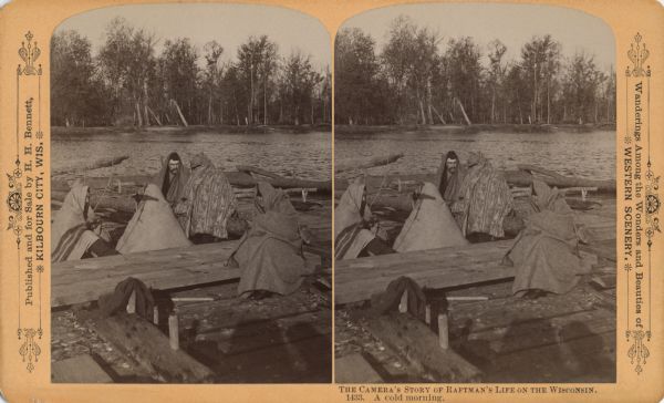 Stereograph of five people huddled under blankets on a raft. The shadow of a camera and the photographer are in the foreground.