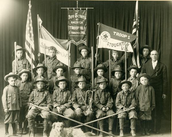 Stoughton, Wisconsin Boy Scouts of America Troop No. 1 group portrait with a dog in the front of the group. One of the members is holding a trumpet.
