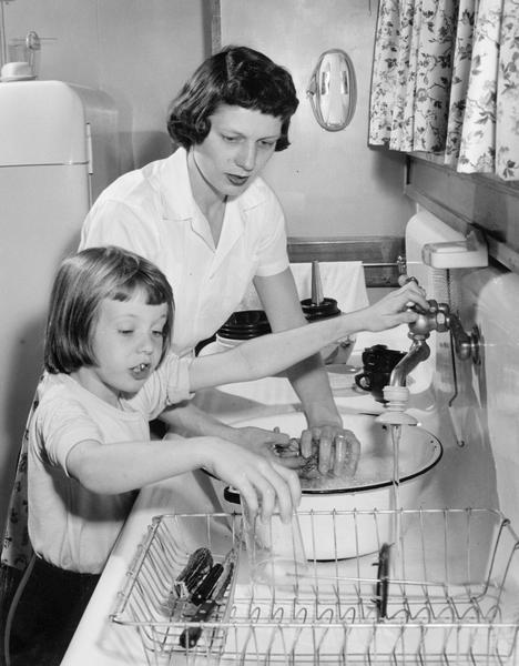 Mother and daughter washing dishes together.