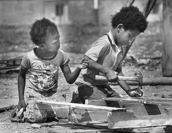 Two young boys using hammers and nails.