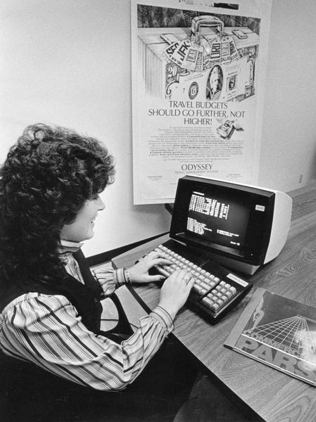 A woman uses an early commercial computer network that allows travel agents to book their own flights without the use of a telephone.