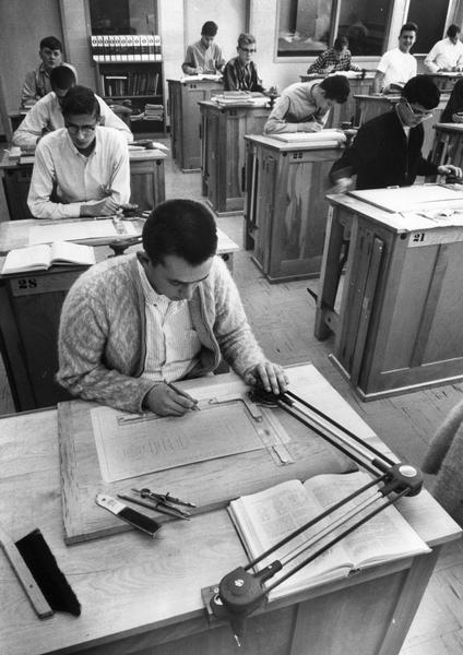 High school boys in an industrial drafting class using drafting machines and compasses.