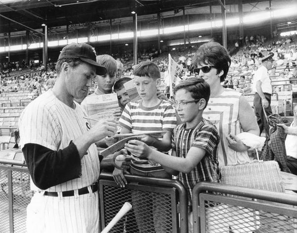 Chicago White Sox pitcher, Don McMahon, signs autographs for fans before a game.