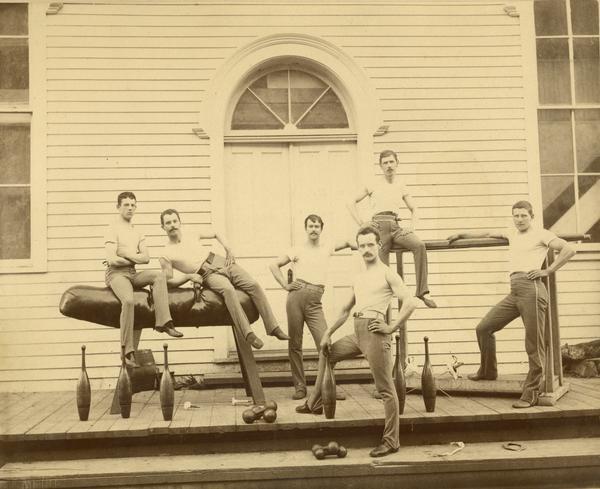 A male gymnastics team posing in front of a building.