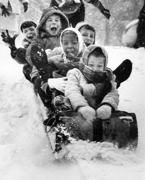 A winter scene with excited children on a toboggan.