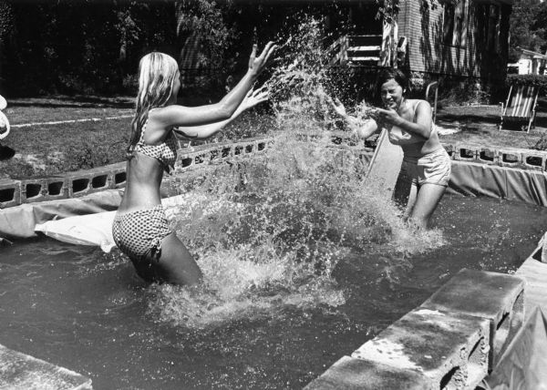 To escape the heat, teenage girls have a water fight in the backyard pool they built.