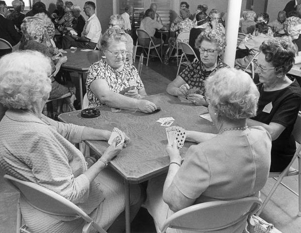 Elderly women sit around a card table and play cards at a new senior center.