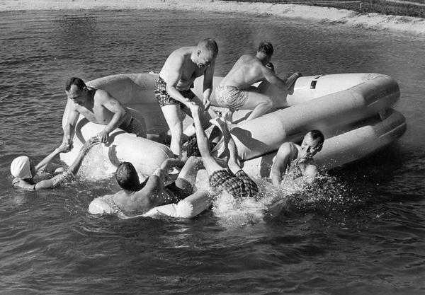 A rubber raft serves as the launching point for diving and other water play on a hot summer day.