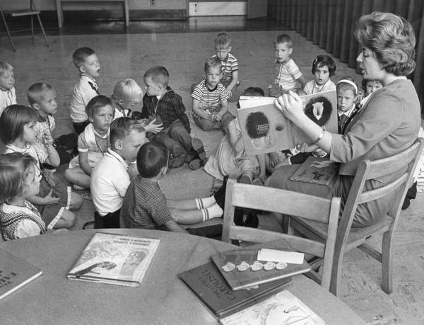 A librarian reads a children's book aloud to young boys and girls.