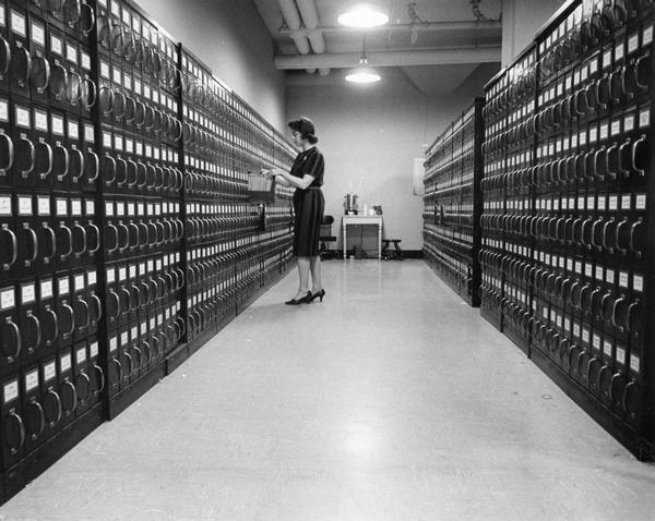 A clerk checks real estate property information in a vast filing system housed in a vault.