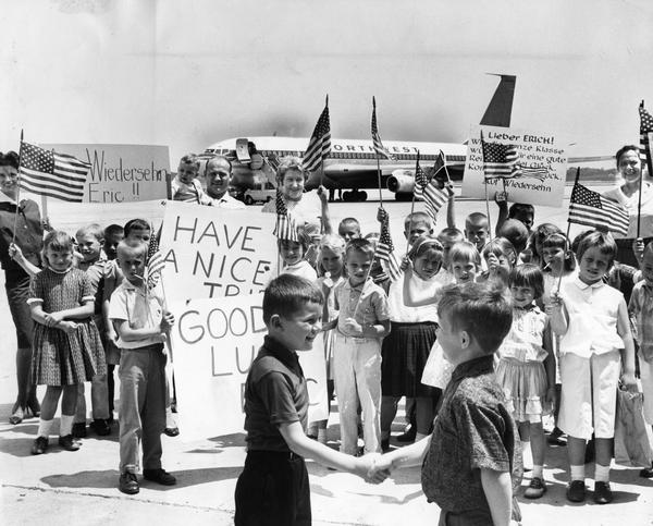 Children, adults, and a Northwest Airlines Boeing 707 jetliner on the tarmac at General Mitchell International Airport. The children, all first graders from Happy Hollow School, were on a field trip to say farewell to a classmate who was about to depart with his mother to visit relatives in West Germany. Milwaukee had entered the jet age only two years earlier with the arrival of a Northwest Airlines Boeing 720.