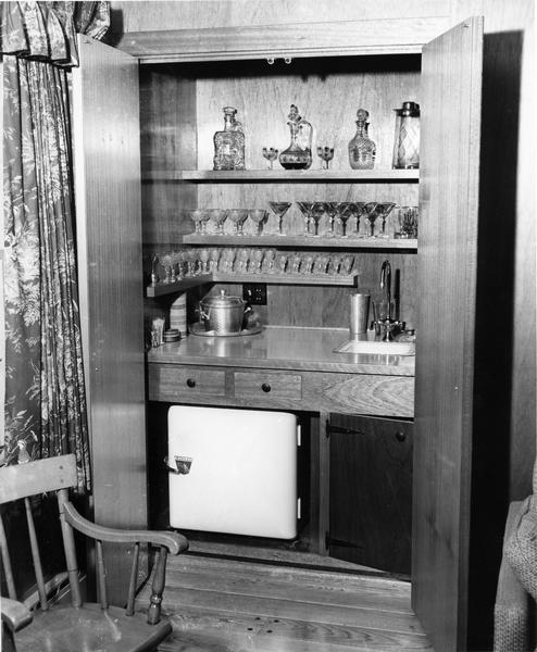 Mini bar with refrigerator and glassware.