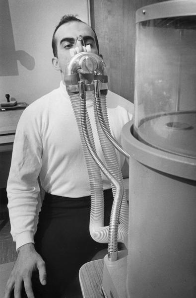 A man exhales into a spirometer to measure his vital lung capacity while at rest.