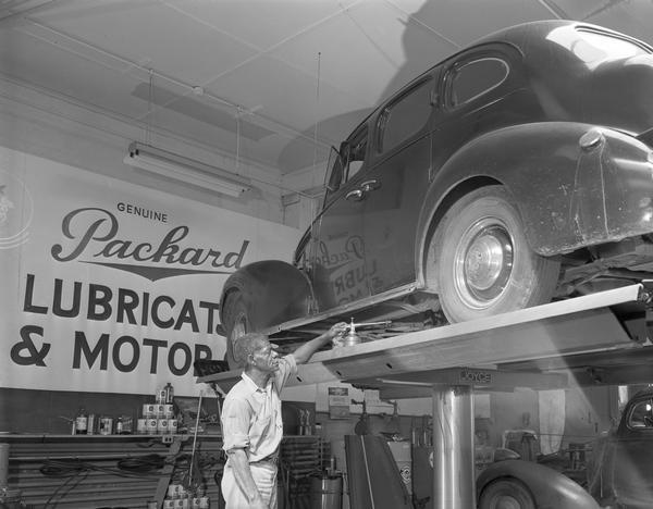 An African American mechanic works on a car up on the rack for servicing at the gas station Meehan Motor Mart, 209 East Washington Avenue.