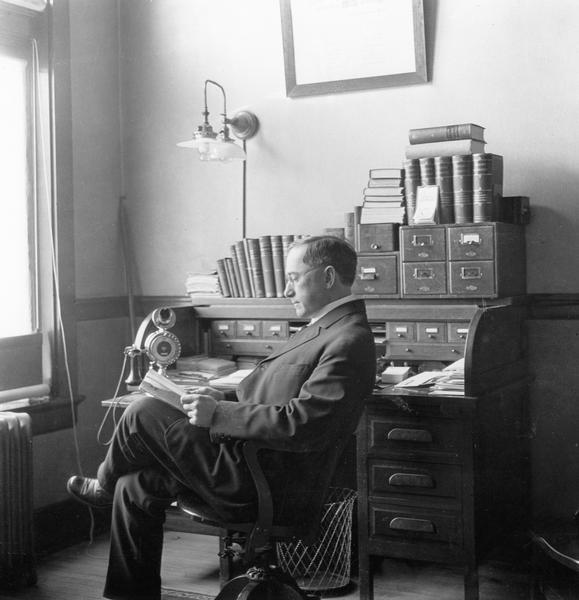Dr. Joseph Smith reads at his desk in his office in the Wisconsin Valley Trust Building.