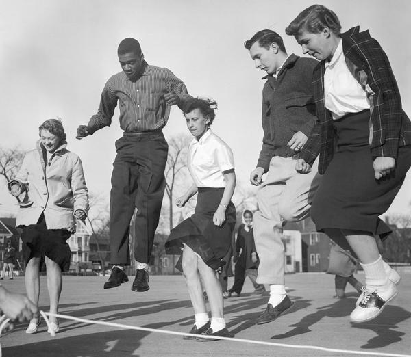 Male and female teenagers participate together jumping rope.
