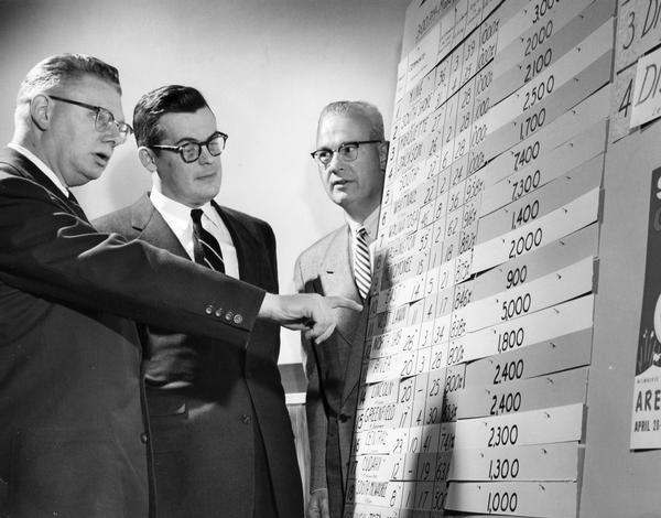 Men looking over charts at a Boy Scout circus ticket sales meeting.
