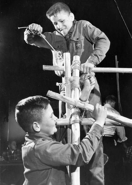 Boy Scouts lash together lengths of wood as they put up an exhibit about pioneering for Scout-O-Rama.