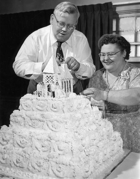 Mr. and Mrs. Wallace Braatz top off the 26-layer wedding cake that Mrs. Braatz made for their daughter's wedding.